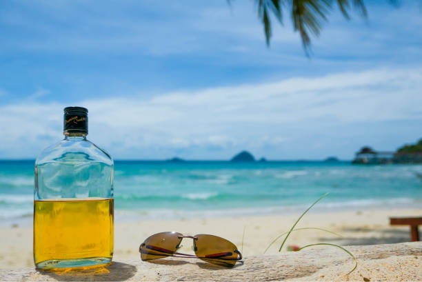 rum and sunglasses on sunny beach stock photo