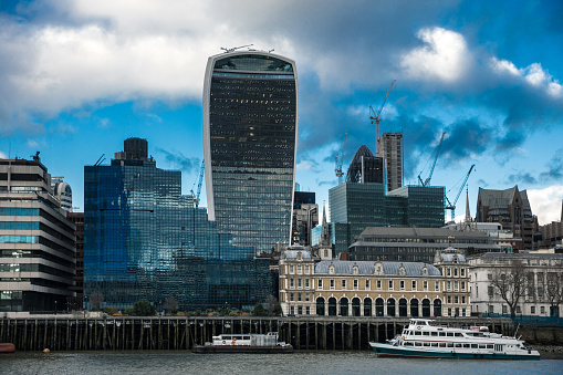 London, UK - May 16th 2015: Barges and the Dixie Queen paddle steamer on the River Thames in front of the Tower of London and Walkie Talkie and Gherkin buildings.