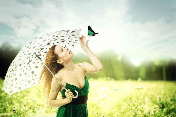 istock woman with umbrella walking though a park playing with butterfly 673219586