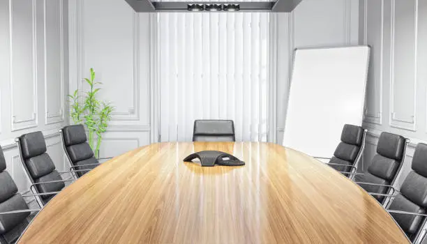 Interior of an empty modern boardroom / conference room with desk, chairs and conference phone.