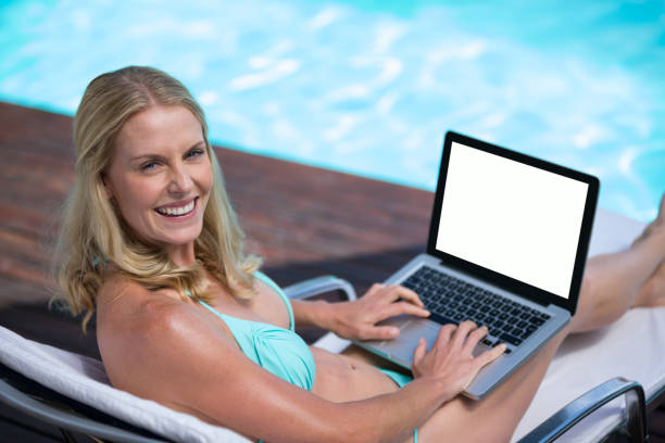 istock Beautiful woman in bikini using a laptop near pool 673219828