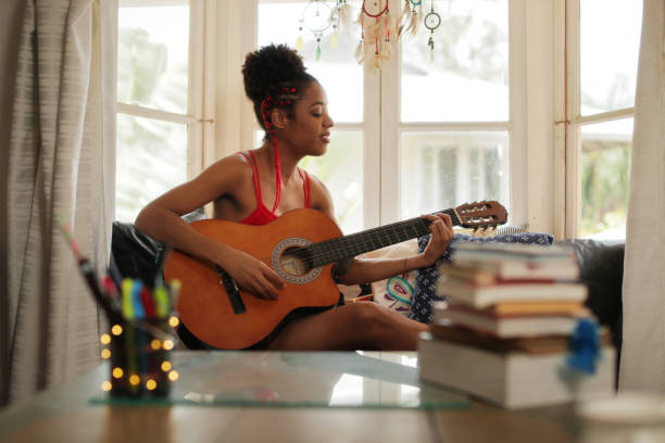 ragazza di razza mista che canta e suona la chitarra classica a casa - lyricist foto e immagini stock