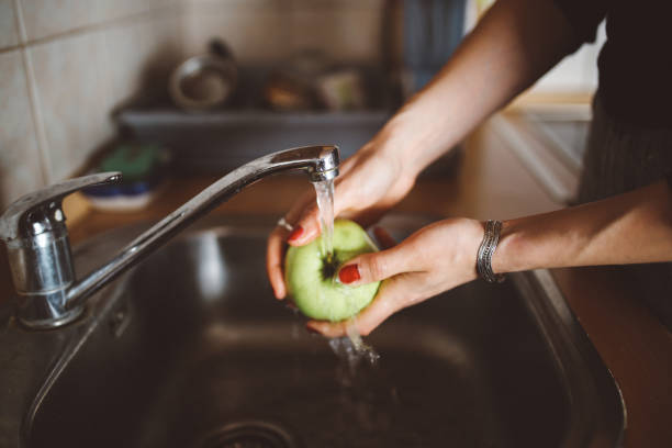 istock Young woman in the kitchen washing an apple 673226310