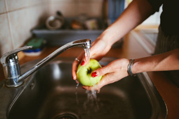 istock Young woman in the kitchen washing an apple 673226912