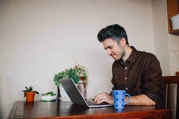 istock Young man working at his laptop in the apartment 673227166