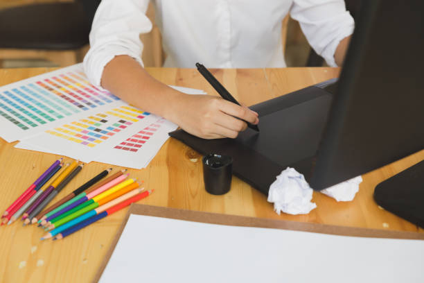 istock freelance graphic designer drawing on digital tablet. woman working with color swatch catalog samples for selection - Creativity Editor Ideas Concept 673232996