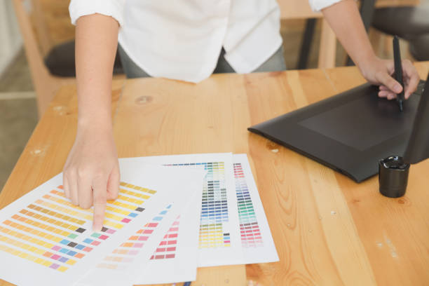 istock freelance graphic designer drawing on digital tablet. woman working with color swatch catalog samples for selection - Creativity Editor Ideas Concept 673233010