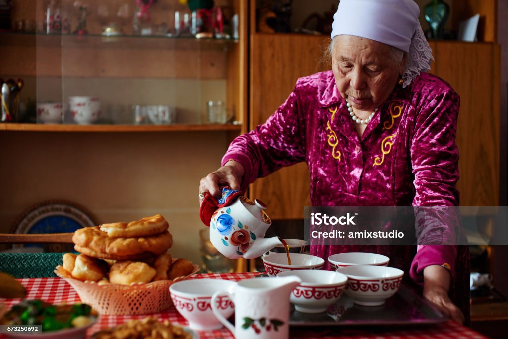 Kazakh grandma pours tea Kazakh grandmother in national clothes pours tea Kazakhstan Stock Photo