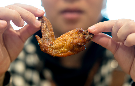 girl eating fried chicken wing