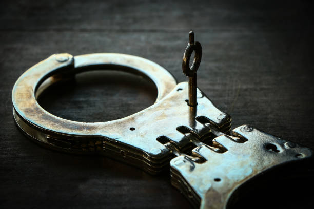 istock Handcuffs on old wooden table 673269504