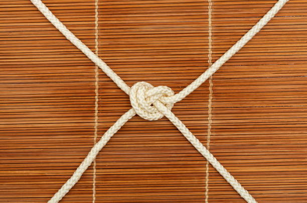 Knot of rope Knot of rope with four ends, on a wooden background bondi junction stock pictures, royalty-free photos & images
