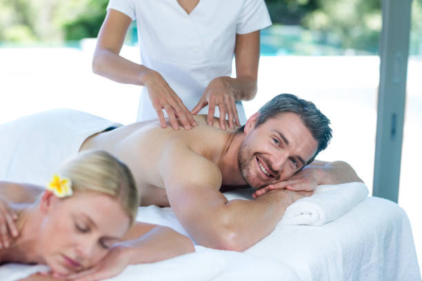 Man receiving back massage from masseur in spa