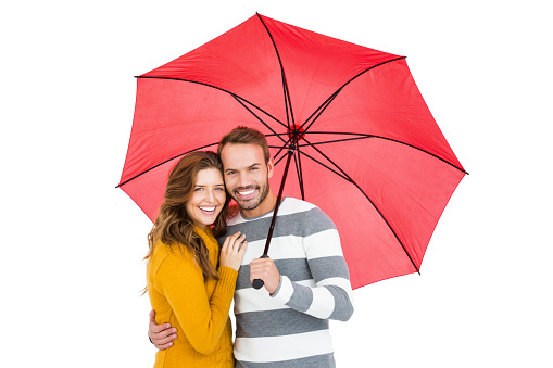 Portrait of happy young couple holding pink umbrella together on white background