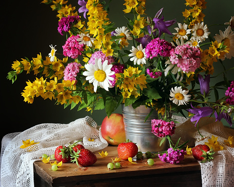 Still life with flowers and fruits. Camomile, carnation, gooseberry, strawberry, apple. July.