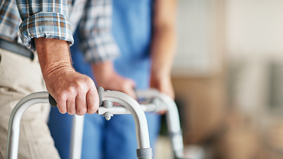 Shot of a woman assisting her elderly patient who's using a walker for support
