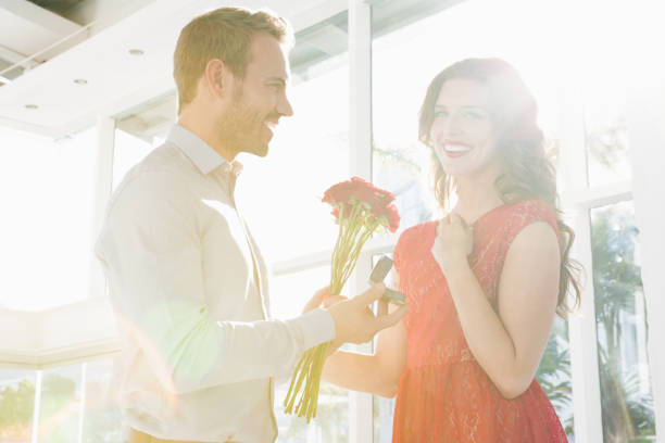 istock Man offering flowers and engagement ring 673337802