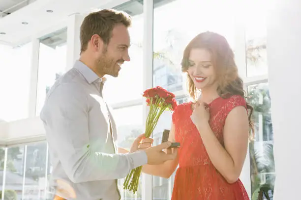 Photo of Man offering flowers and engagement ring