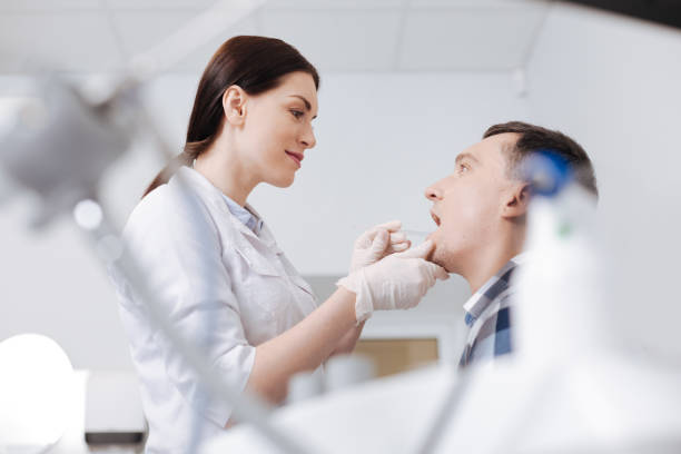 concorridas médico olhando na boca de seu paciente - throat exam - fotografias e filmes do acervo