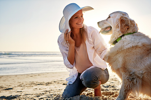 Shot of a mature woman taking her dog for a walk on the beach
