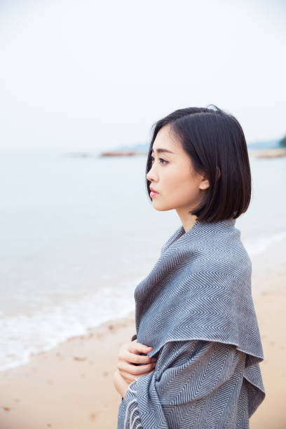 istock Beautiful woman with grey scarf standing on beach 673351226