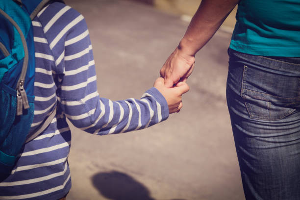 istock going to school- mother holding hand of son 673357370