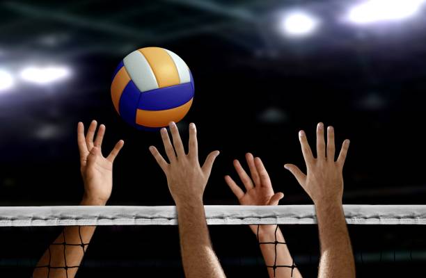 Volleyball spike hand block over the net hand blocking volleyball spike over the net inside of a stadium volleyball stock pictures, royalty-free photos & images