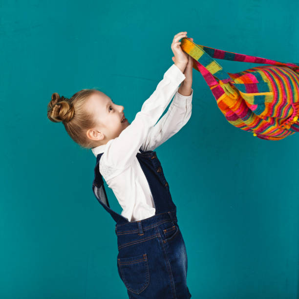 istock Beautiful smiling little girl with big backpack standing against blue wall 673367974