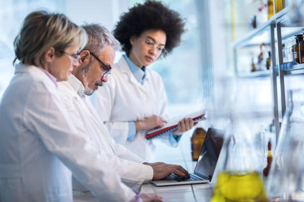 groupe de médecins, analyse des données médicales sur l’ordinateur portable dans le laboratoire. - scientist research group of people analyzing photos et images de collection