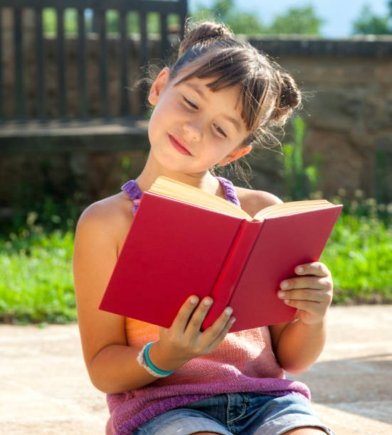 istock Little happy girl reading a book 673372336