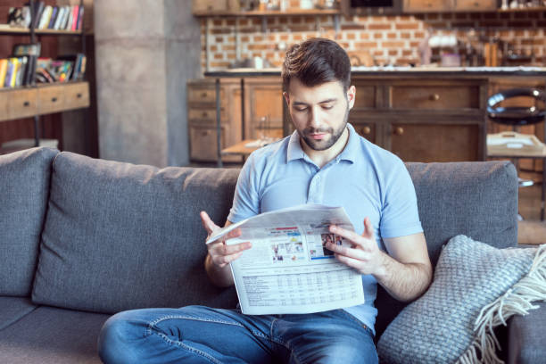 istock concentrated man sitting on coach and reading newspaper 673375396