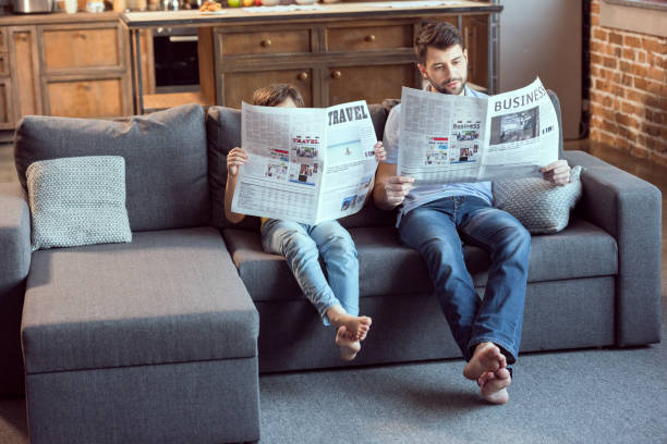 istock father and son sitting on couch and reading newspapers 673378850