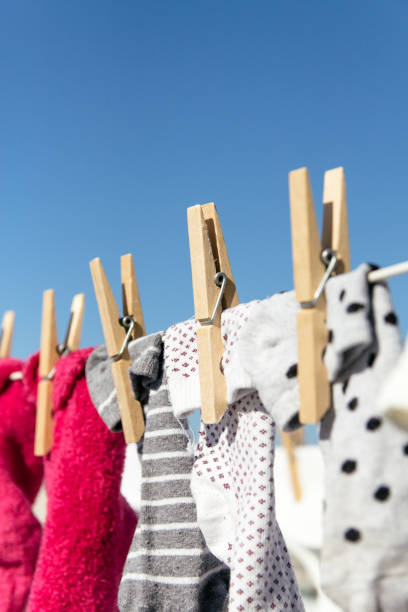 Colorful socks hung out to dry on a washing line in the bright warm sun. Background is a clear blue sky. stock photo
