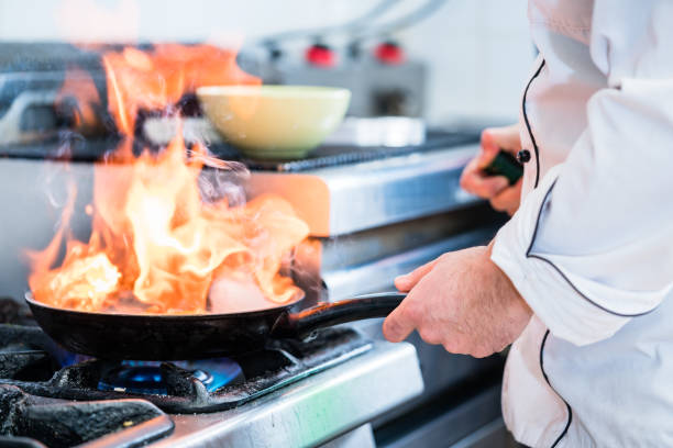 istock Chef doing flambe to dish in pan 673382544