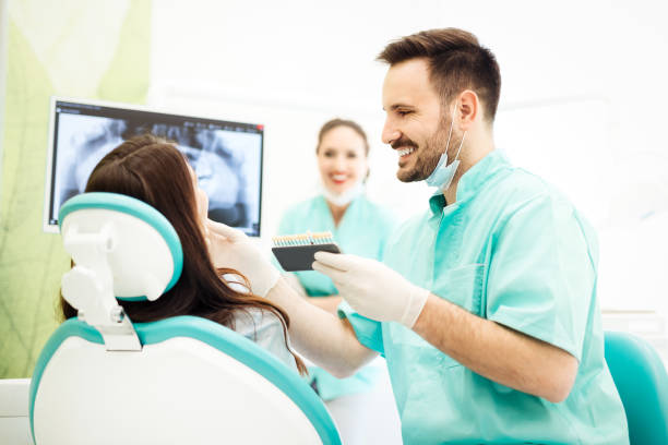 istock Dentist checking and selecting color of young woman's teeth 673382904