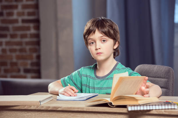 istock portrait of serious boy sitting at table and doing homework 673386158