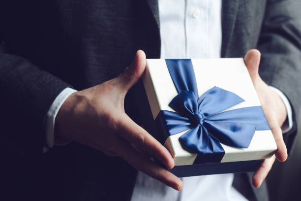 Man offering gift with blue ribbon stock photo