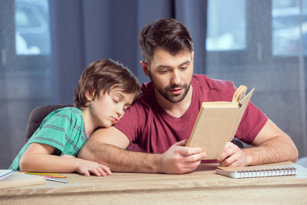 istock father reading book to sleeping son on shoulder 673387470