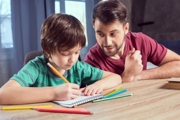 istock side view of father looking at concentrated son doing homework 673387780