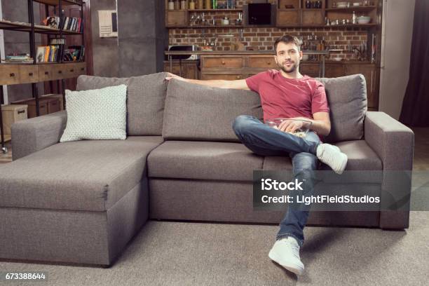 Man Eating Popcorn And Watching Movie At Home Stock Photo - Download Image Now - Sofa, Men, Sitting