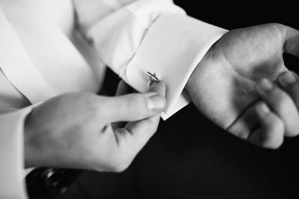 istock Black and white. Preparing for wedding. Groom buttoning cufflinks on white shirt before wedding. True men's accessory. Groom's clothes. Close up. 673391066