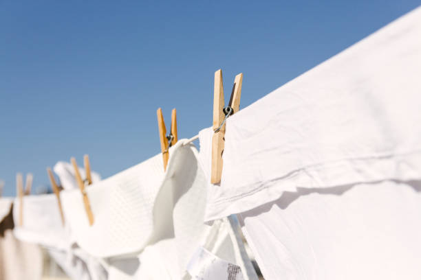 White clothes hung out to dry on a washing line in the bright warm sun. Background is a clear blue sky. White clothes hung out to dry on a washing line in the bright warm sun. Background is a clear blue sky. drying photos stock pictures, royalty-free photos & images