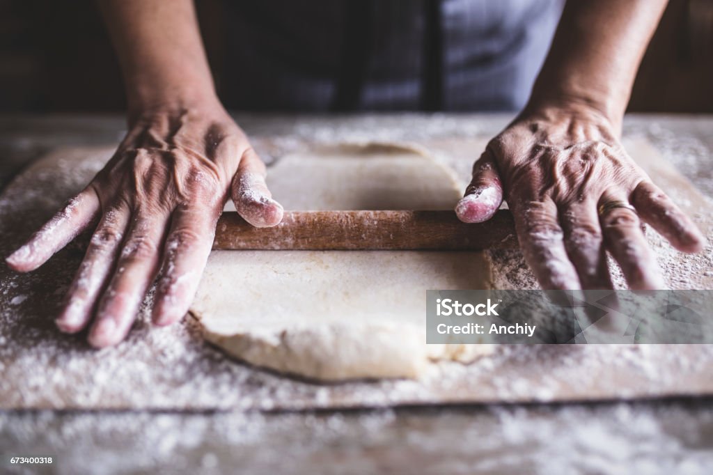 Hands baking dough with rolling pin on wooden table Hand Stock Photo