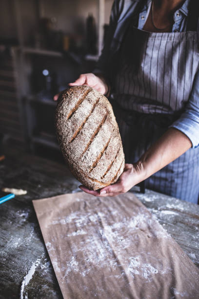 istock Woman wearing apron holding bread in her kitchen 673401846