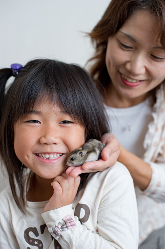 Parent and child playing with pet rat