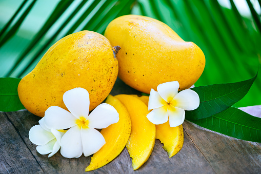 Fresh mango and white flower on the wooden table and green background