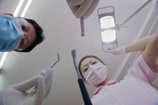 Caucasian male dentist examining the female patient mouth, during monthly control