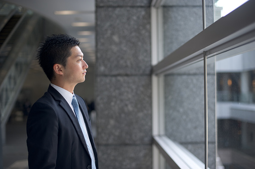 A colleague businessman looking out in the office building