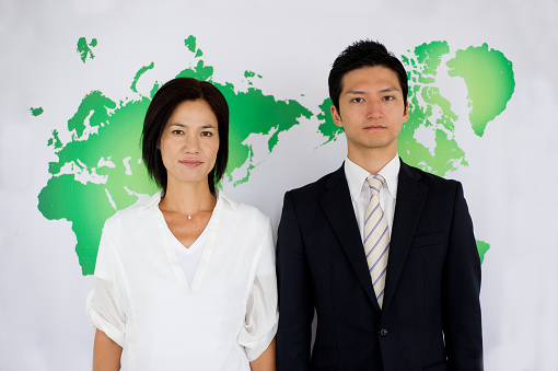 A smiling businessman with a beautiful colleague against the background of the world map