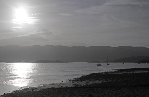 Sun shining down on small boats moored on the Kyles of Bute and the Colintraive shoreline