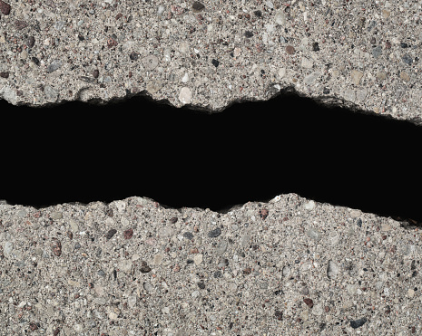 Close up of hole in the cracked road isolated on black background with copy space